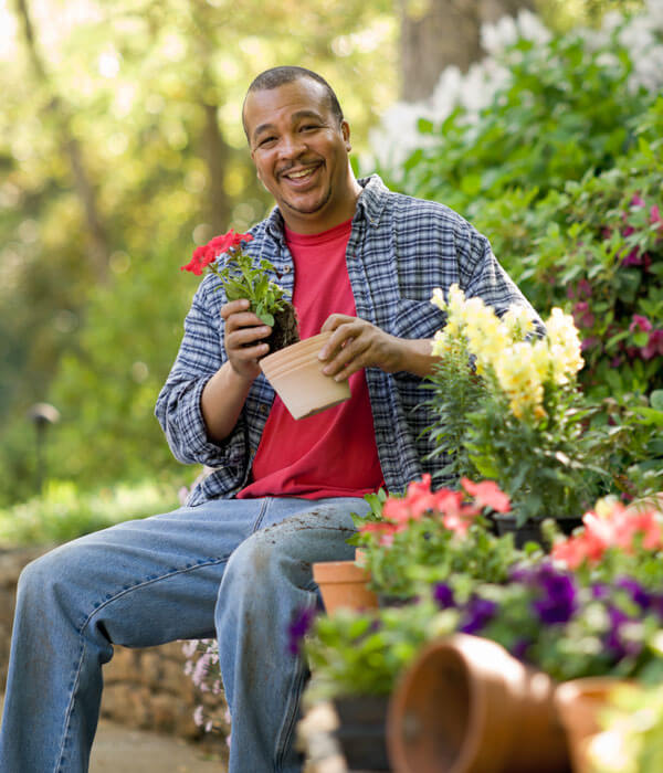adult man smiling and gardening in his backyard