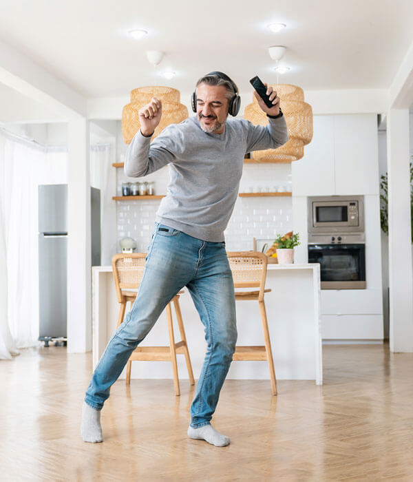 mature man with headphones dancing in his living room
