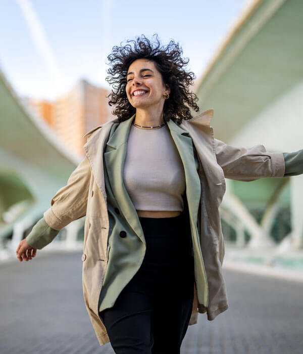 woman is smiling and skipping down a city street
