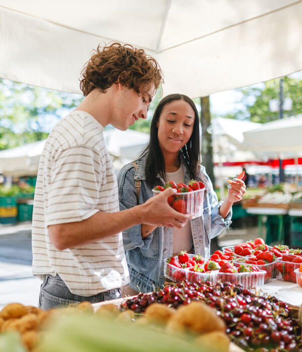 young couple at a farmer's market inspecting strawberries