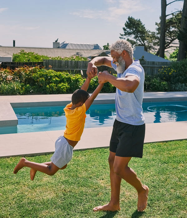 a dad swinging his son around in the backyard