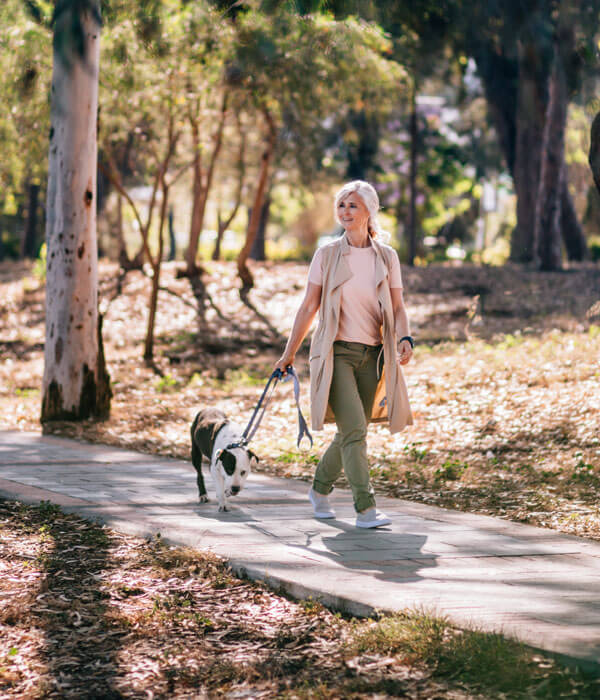 mater woman walking her dog in a park