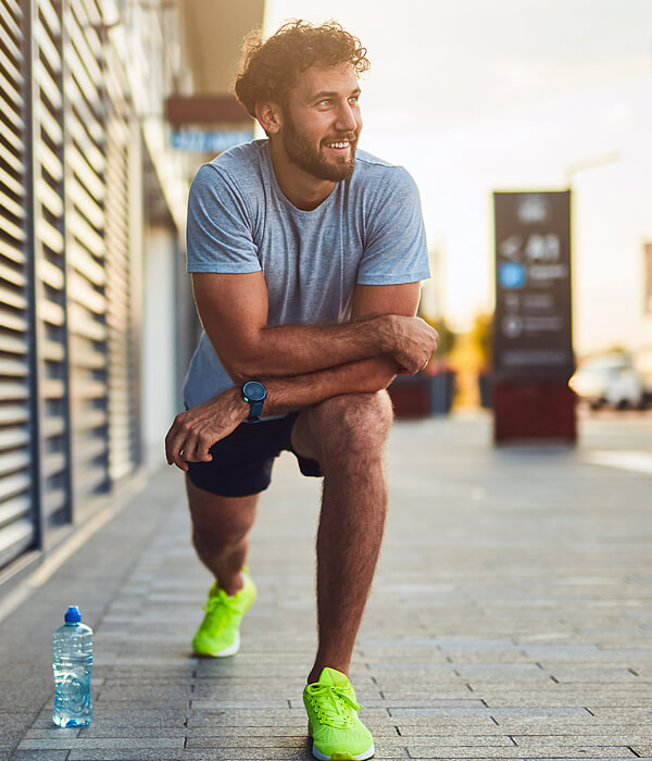 smiling man stretching on a sidewalk